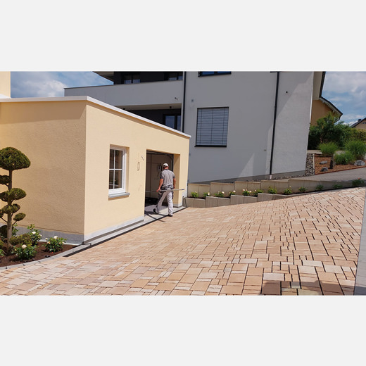 Die angebaute Garage und der neu gepflasterte Hof erstrahlen in hellem Beige.